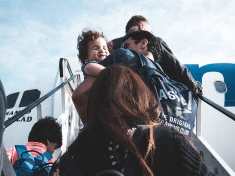 子供をだっこして飛行機に搭乗する家族