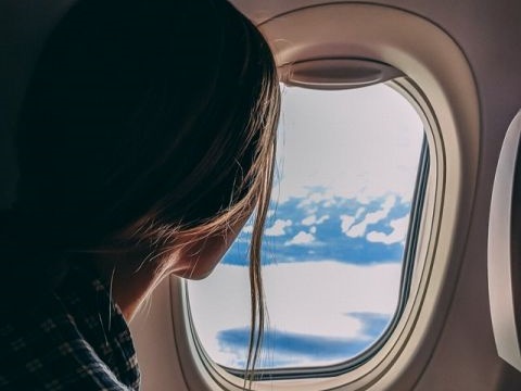 機内の窓から心配そうに外をみる女性