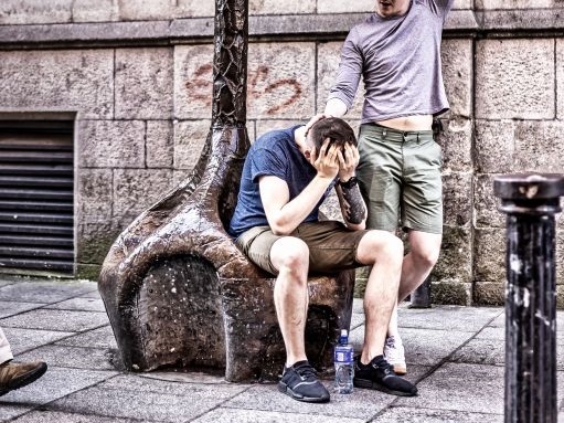 泥酔して同僚に介抱してもらう男性